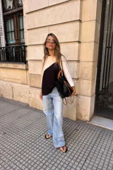 Remerón de manga tres cuartos con diseño tricolor en bloques diagonales: negro en el centro, beige claro en la parte superior izquierda y blanco en la manga derecha.