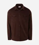 Camisa de hombre de corte regular confeccionada en terciopelo color beige. Presenta cuello clásico, cierre frontal con botones y dos bolsillos con solapa en el pecho.