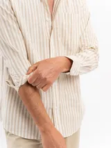 Camisa de manga larga con diseño de rayas verticales en tonos beige y blanco, cuello camisero y cierre frontal con botones.