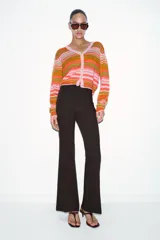 Chaqueta de punto con cuello pico y manga larga, con cierre frontal de botones. Presenta un estampado de rayas horizontales en tonos rosado, naranja y verde.