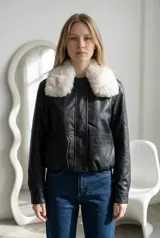 Campera de ecocuero negro con cuello de piel sintética desmontable, cierre frontal oculto y bolsillos laterales.