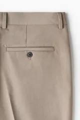 Pantalón de vestir color beige, de corte slim fit, con pinzas marcadas en el frente y dobladillo en el bajo.
