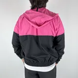 Campera deportiva con capucha, combinada en fucsia y negro, con cierre frontal y bolsillos laterales.