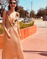 Vestido midi de satén en tono dorado verdoso, con escote en V profundo decorado con un mix de cueros unidos artesanalmente. Presenta tajos laterales, espalda descubierta y un diseño fluido con gran movimiento.