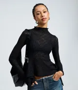 Blusa de encaje floral negro con cuello alto y mangas largas. Presenta un diseño ajustado en el torso con un detalle peplum en el ruedo que aporta volumen y movimiento.