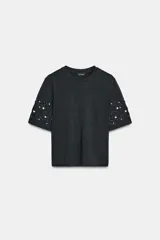 Camiseta de manga corta y cuello redondo, color negro oscuro, con detalle de bordados en forma de espiral con aplicación de abalorios y perlas en las mangas.