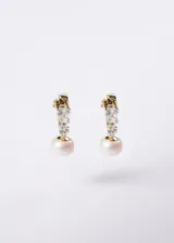 Aros colgantes de plata 925 con baño de oro 18k, diseñados con una tira de tres zirconias cúbicas y una perla cultivada colgante en el extremo.