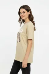 Remera de algodón color beige con estampado frontal de un corazón rosado que contiene un moño. Tiene cuello redondo y mangas cortas.