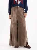 Pantalon de cuero ovino gris con diseño de pata ancha y recortes geométricos a la altura de las rodillas.