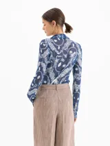 Camisa de mesh elastizado color azul con estampado de cadenas, de manga larga y suave transparencia, con drapeado en el centro delantero.