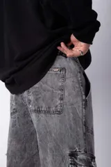 Pantalón cargo de jean con efecto lavado ácido en tono gris. Presenta bolsillos laterales tipo cargo, bolsillos frontales amplios y corte holgado.