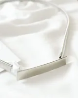 Cinturón plateado de metal con eslabones elásticos y hebilla rectangular.