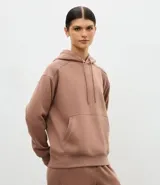 Buzo deportivo oversized con capucha, confeccionado en mezcla de algodón y poliéster. Presenta bolsillo frontal tipo canguro, mangas con recortes en los hombros y puños y ruedo con terminación en rib.