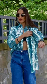 Chaqueta celeste con lentejuelas, corte tipo camisa, de manga larga y con bolsillos frontales.