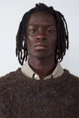 Sweater de cuello redondo con diseño de bloques de color en tonos marrón, gris y blanco, con textura de tejido de punto esponjoso y mangas largas.