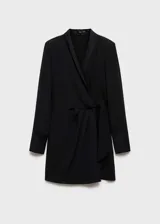 Vestido corto de color negro con diseño cruzado, cuello en pico con solapa tipo blazer y manga larga. Presenta un lazo en la cintura que permite ajustar la prenda y un tejido fluido y ligero con forro interior.
