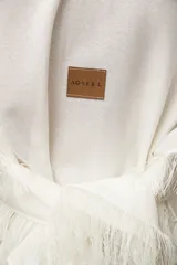 Chal de tejido liviano con lino, color blanco, con terminaciones desflecadas y diseño versátil para usar como capa.