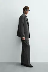 Blazer oversized fit de hombre, color gris oscuro con rayas verticales finas. Cuello con solapas de muesca, manga larga con puño abotonado, bolsillos de solapa en la cadera y bolsillo interior. Cierre frontal de un botón y abertura en el centro de la espalda.