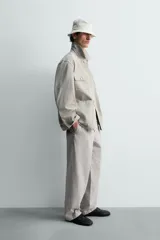 Cazadora de corte relajado confeccionada en tejido de algodón compacto con efecto lavado. Presenta cuello de solapa, manga larga con puños abotonados y cierre frontal de botones. Incluye cuatro bolsillos frontales: dos de plastrón con solapa en el pecho y dos bolsillos dobles de plastrón en la cadera.