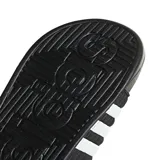 Sandalias tipo slide Adidas Adissage, color negro con tres franjas blancas en la tira superior ajustable con velcro. La plantilla presenta un diseño texturizado con protuberancias para masaje.