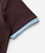 Remera marrón de manga corta con cuello redondo y ribetes celestes en cuello y puños. Presenta un gran estampado numérico "86" en color celeste en el pecho.