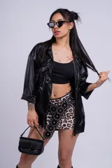Camisa marrón de cuero sintético, con cuello clásico, cierre frontal con botones a presión y bolsillos con solapa en el pecho.