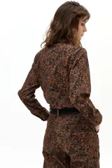 Camisa de pana de algodón con estampado floral multicolor sobre base verde, cuello clásico, botones forrados y corte ligeramente más largo en la parte posterior.