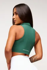 Top deportivo negro, estilo crop top, con cuello polo y escote en V. Presenta tirantes anchos y corte ajustado al cuerpo.