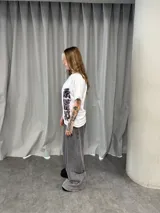 Remera blanca de algodón con estampado gráfico estilo oriental en colores rosa y negro. Presenta un diseño asimétrico con caracteres en la parte superior derecha y lateral inferior izquierdo.