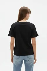 Remera blanca de algodón, de corte ajustado, con cuello redondo y mangas cortas terminadas con volados delicados.