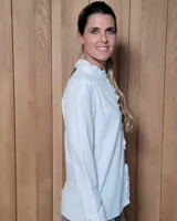 Camisa blanca de algodón con cuello alto tipo mao y volados sutiles a lo largo de la botonadura frontal. Presenta mangas largas con frunces en los hombros y botones frontales.