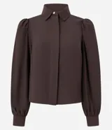 Camisa de crepé color blanco, con cuello inglés, manga larga abullonada con puños abotonados y cierre frontal oculto con botón diferenciado en el cuello.
