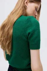 Buzo de punto suave con cuello redondo y mangas cortas. Presenta un diseño entallado con terminaciones acanaladas en cuello, puños y ruedo.