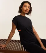 Remera deportiva negra de microfibra de poliamida, con cuello redondo, mangas cortas y franja lateral contrastante color naranja.