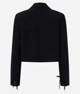 Blazer corto de sastre de la marca Cortelle, color negro, confeccionado en poliéster. Cuenta con cuello con solapa, mangas largas con amarre en los puños, bolsillos delanteros y cierre frontal por cordón ajustable con punteras metálicas.