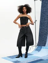 Top tipo corset confeccionado en denim negro, con escote strapless y cierre frontal con cremallera.