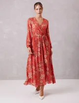 Vestido midi de gasa estampada con diseño floral, escote en V cruzado, cintura elastizada con lazo de ajuste y mangas largas con puños fruncidos. Incluye forro interno a tono.