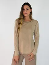 Remera de manga larga en color beige, confeccionada en tejido de algodón con acabado desgastado. Presenta un cuello redondo con detalle de borde desflecado y costuras visibles que le otorgan un estilo casual y relajado.