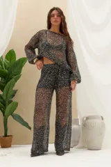 Pantalón largo negro con lentejuelas y acabado brillante, de corte recto y tejido semitransparente.