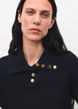 Jersey de punto acanalado con cuello polo y cierre frontal de botones decorativos. Presenta un diseño recto de manga larga.