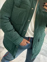 Campera verde militar acolchada con cuello camisero, cierre frontal con botones a presión, bolsillos de parche con solapa en el pecho y bolsillos laterales.