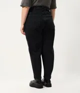 Pantalón de jean estilo mom, color negro, tiro alto, corte holgado en caderas y piernas, con bolsillos funcionales y cierre frontal.
