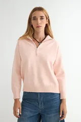 Buzo de punto con medio cierre frontal, cuello alto y mangas largas con puños acanalados. Presenta un diseño liso en color rosa suave con terminación acanalada en el ruedo.