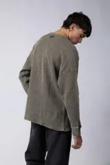 Buzo de corte oversize confeccionado en tela waffle de algodón con proceso de teñido acid wash. Presenta cuello redondo con detalle de costura en X y mangas largas con puños acanalados.