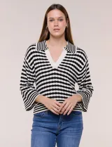 Blusa tejida de punto a rayas horizontales blancas y negras, con cuello polo y escote en V profundo. Presenta hombros caídos, mangas 3/4 estilo campana y corte holgado.
