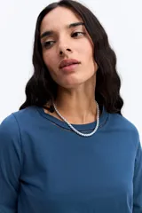 Remera de manga larga color beige, con cuello redondo y detalles calados decorativos en el borde del cuello y en los puños.