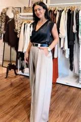 Pantalón de vestir color beige, de corte amplio y tiro alto, con pinzas delanteras y cinturón negro incluido.