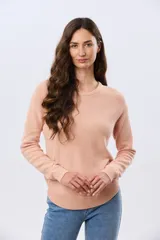 Buzo tejido liso de manga larga con cuello redondo, confeccionado en algodón de tejido grueso. Presenta bordes acanalados en el cuello, los puños y la cintura, con un pequeño detalle de placa metálica en el lateral inferior.