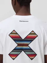 Remera de algodón orgánico color blanco, con corte regular fit y detalle de bordado en forma de X con diseño geométrico multicolor en el pecho.