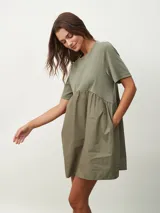 Vestido corto color verde oliva, con corte holgado, mangas cortas y falda con frunce. Tiene bolsillos laterales.